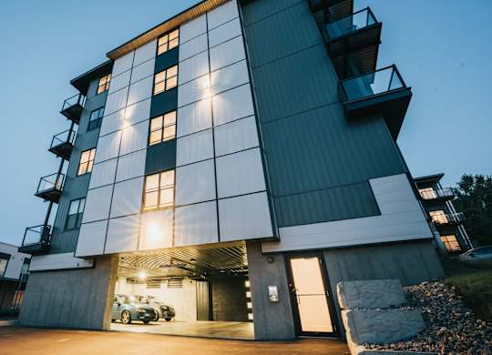 A modern building with a large glass window and a car parked in the garage.