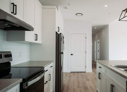 A kitchen with a black counter top and white cabinets.