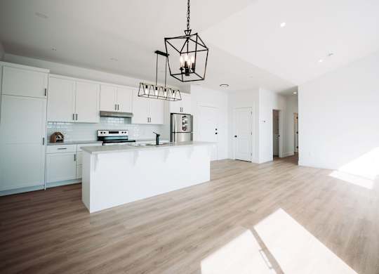 A modern kitchen with white cabinets and a wooden floor.