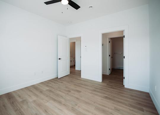 A room with a ceiling fan and wooden flooring.