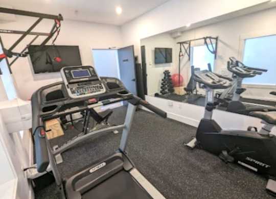 A treadmill and a stationary bike are in a well-lit room.