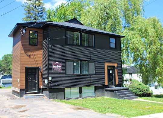 A black house with a red sign on the front.