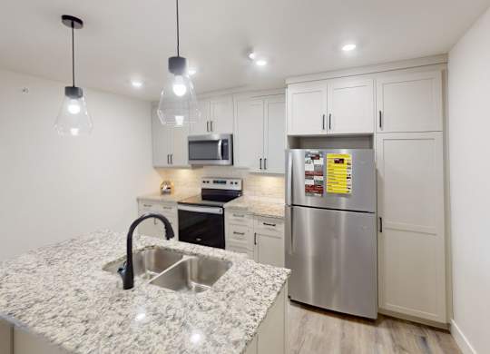 A kitchen with a granite countertop and stainless steel appliances.