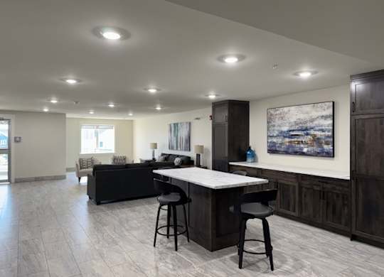 A modern kitchen with a bar area and a painting on the wall.