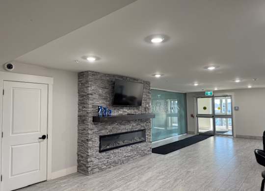 A living room with a stone fireplace and a flat screen TV mounted above it.