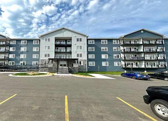 A parking lot in front of a large apartment building.