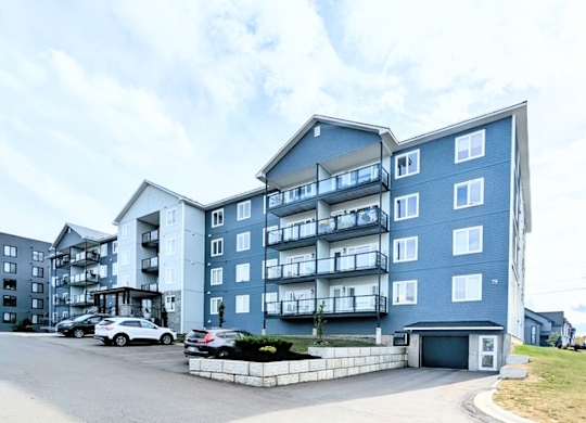 A large blue and white apartment building with cars parked in front.