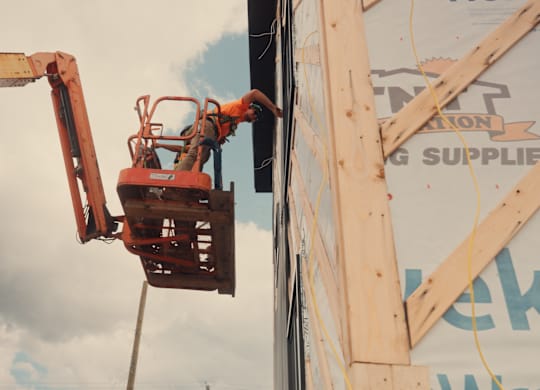 A man is working on a construction site with a cherry picker.