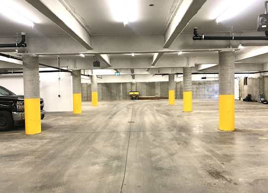 A parking garage with concrete floors and yellow poles.