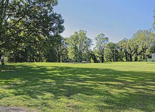 A park with a dirt path and a green grassy area.