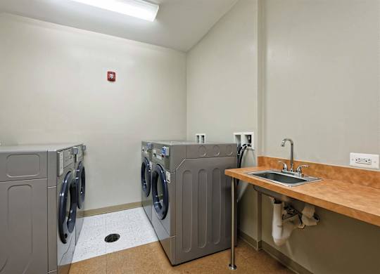 A laundry room with a washer and dryer on the left and a sink on the right.