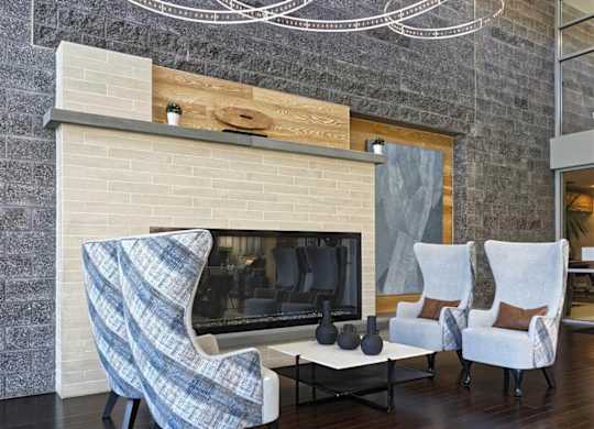 A modern living room with a fireplace and two chairs.