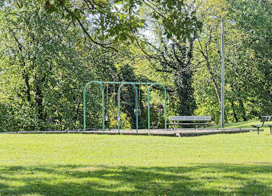 A park with a swing set and a bench.