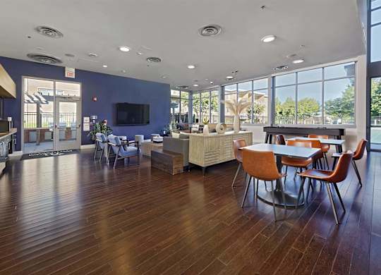 A spacious room with wooden floors and a large window overlooking a tree-filled area.