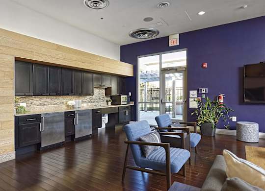 A modern kitchen with a wood grain island and blue chairs.