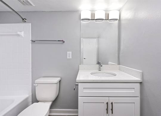 A white bathroom with a toilet, sink, and mirror.