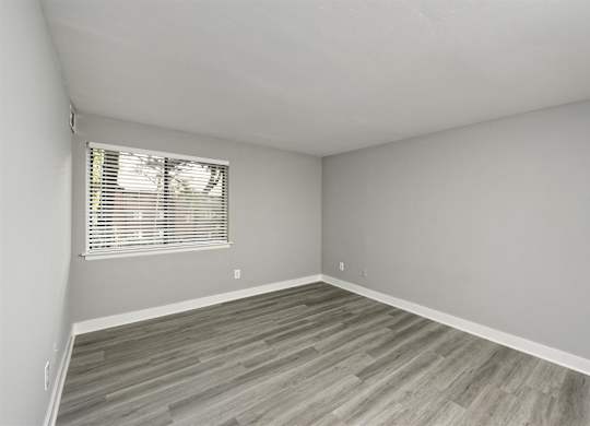 A room with a window and wooden flooring.