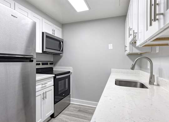 A kitchen with a stainless steel refrigerator, microwave, oven, and sink.