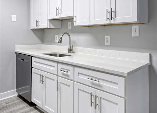 A kitchen with white cabinets and a white countertop.