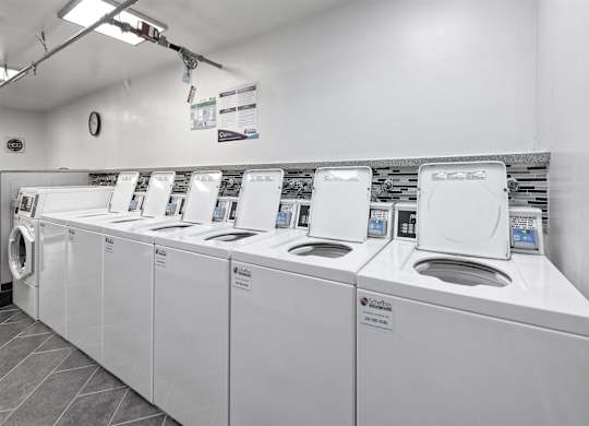 A row of white washing machines in a laundromat.