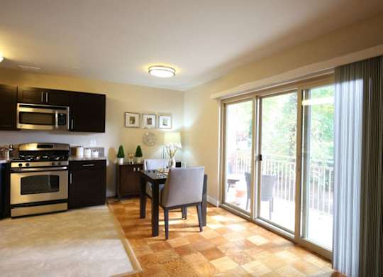 A kitchen with a table and chairs in front of a sliding glass door.