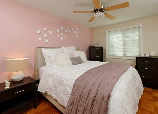 A bedroom with a bed, nightstand, and a ceiling fan.