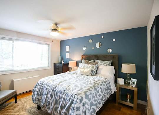 A bedroom with a bed, nightstands, and a ceiling fan.
