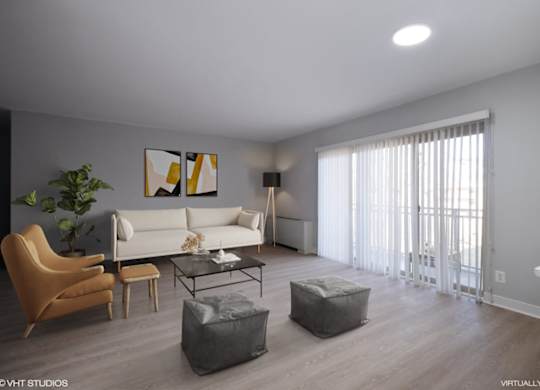 A living room with a white couch, a brown chair, a glass coffee table, and a grey ottoman.