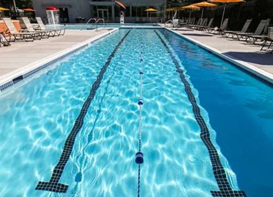 A swimming pool with a clear blue water and a black and white patterned lane divider.