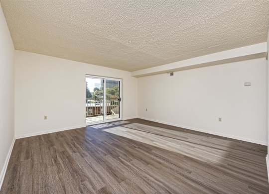 A room with wooden flooring and a sliding glass door leading outside.