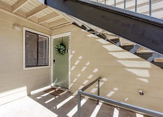 A staircase with a metal railing and a green door.