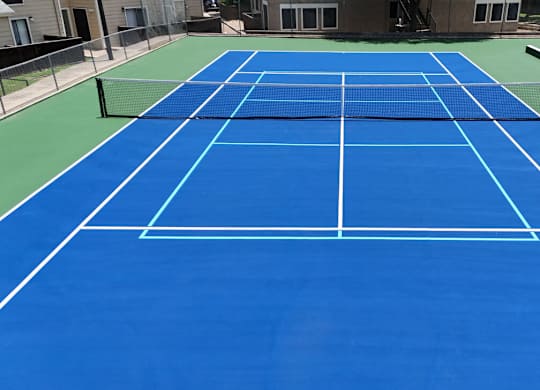 A blue tennis court with white lines and a net.