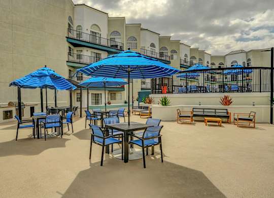 A patio with blue umbrellas and chairs.