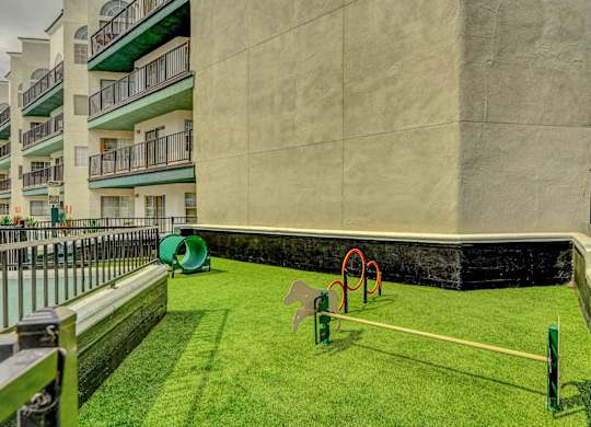 A playground with a green lawn and a white fence.