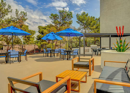A patio with blue umbrellas and wooden furniture.