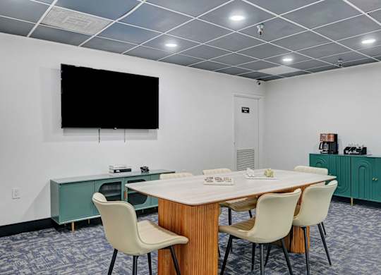 A conference room with a large table, chairs, and a television on the wall.