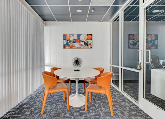 A conference room with a white table and orange chairs.
