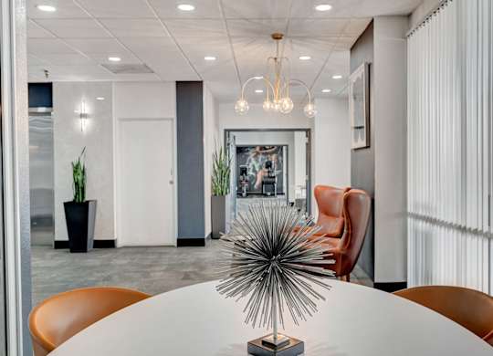 A modern conference room with a white table and orange chairs.