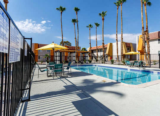 A pool surrounded by palm trees and chairs.