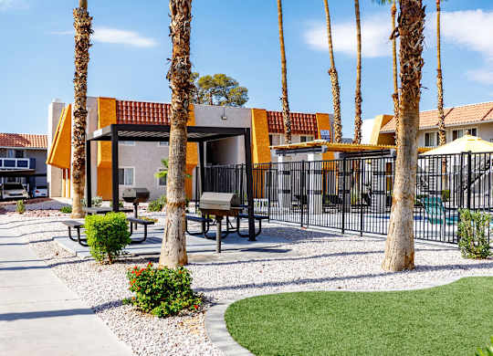 A yellow building with a red roof is surrounded by palm trees.