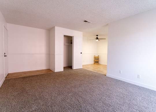 A room with a carpeted floor and a ceiling fan.