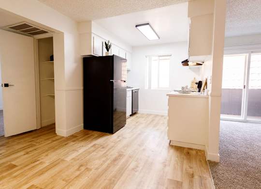 A kitchen with a black fridge and wooden floors.