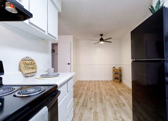 A kitchen with a black refrigerator and wooden floors.