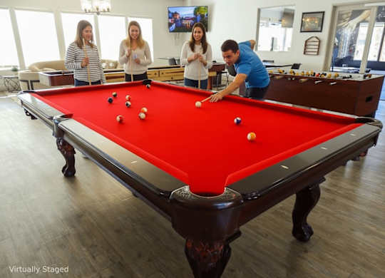 A man is about to take a shot at a pool table with three women watching.