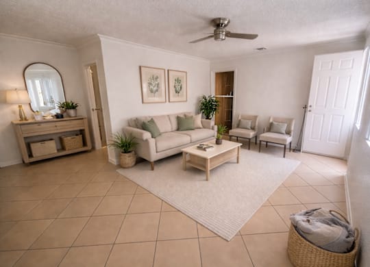 A living room with a white couch, a coffee table, and a ceiling fan.