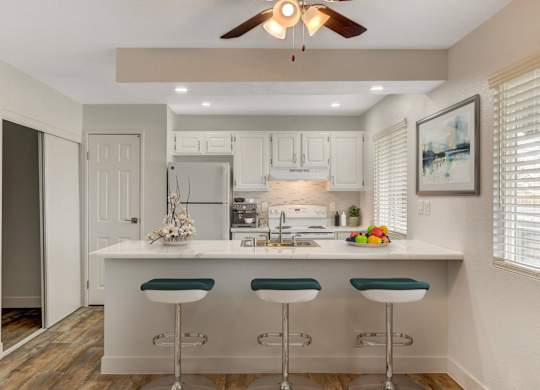 A kitchen with white cabinets and a white island with green bar stools.