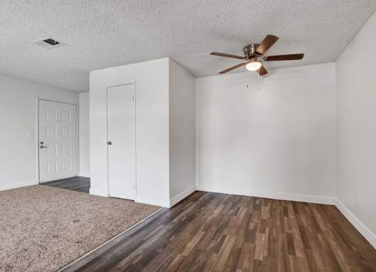 A room with a ceiling fan and two doors.