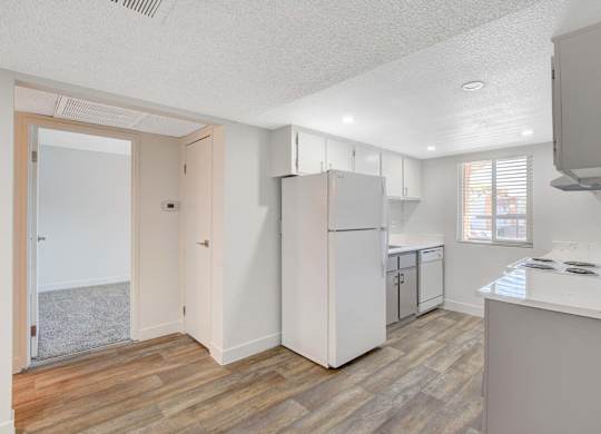 A kitchen with a white fridge and wooden floors.