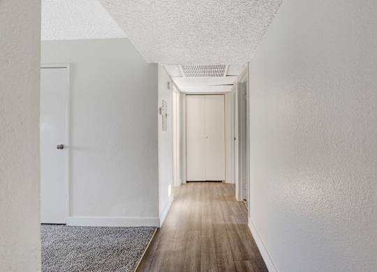 A long hallway with white walls and wood flooring.
