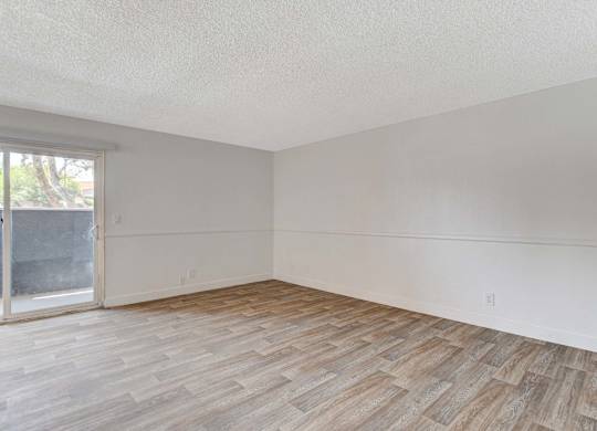 A room with wooden flooring and a sliding glass door.